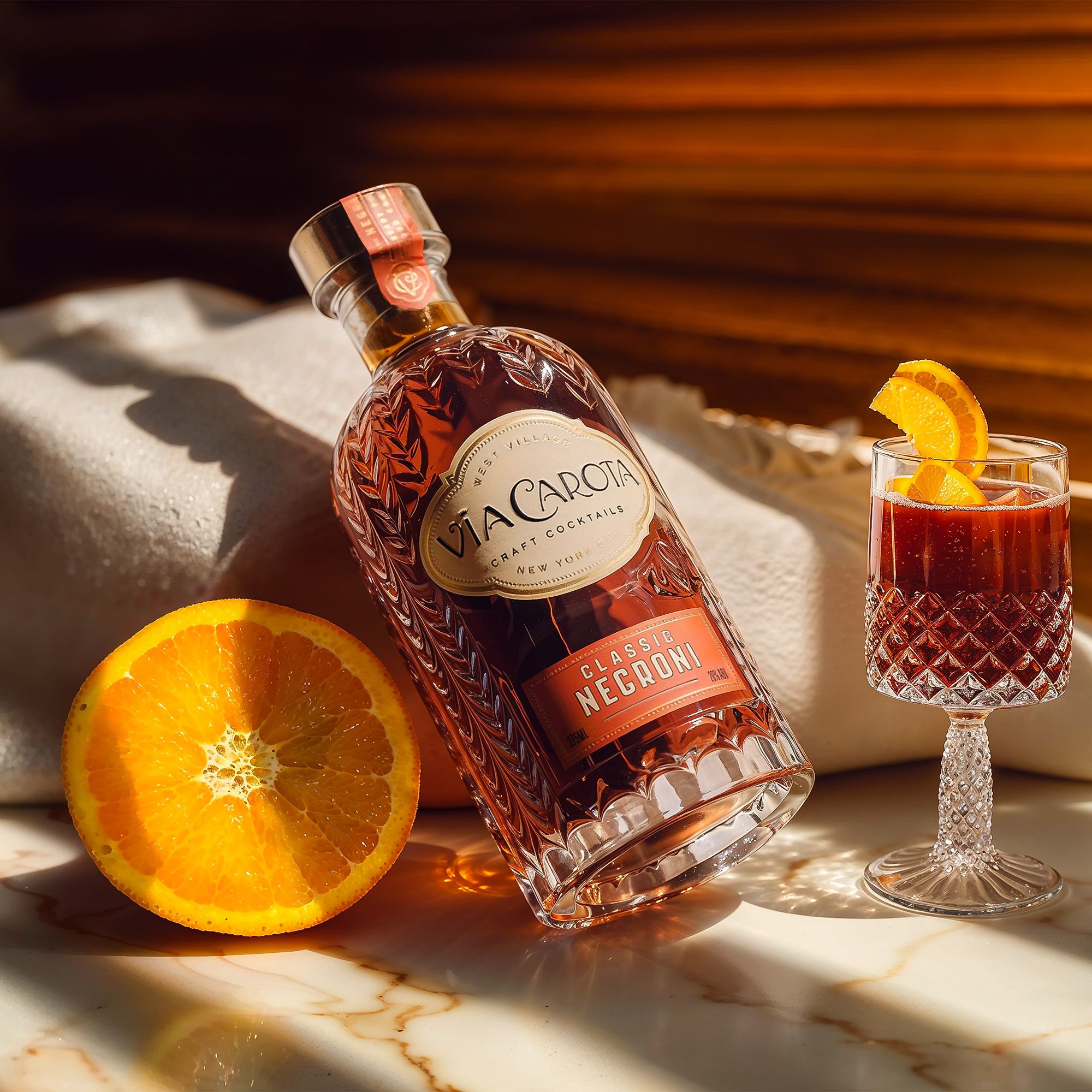 Classic Negroni bottle leaning in warm afternoon sun through Venetian blinds, a garnished glass beside it — Chronos Studio for Via Carota.