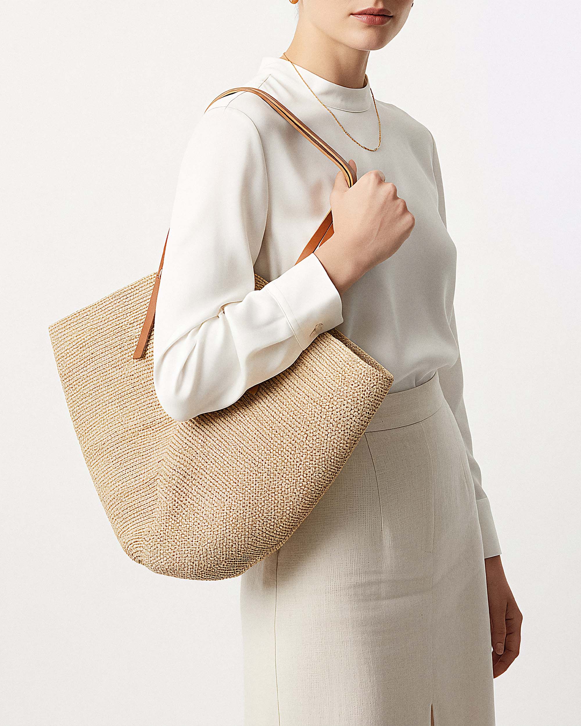 Handwoven raffia bag photographed to Bloomingdale's retail specification on a clean warm set — Chronos Studio.