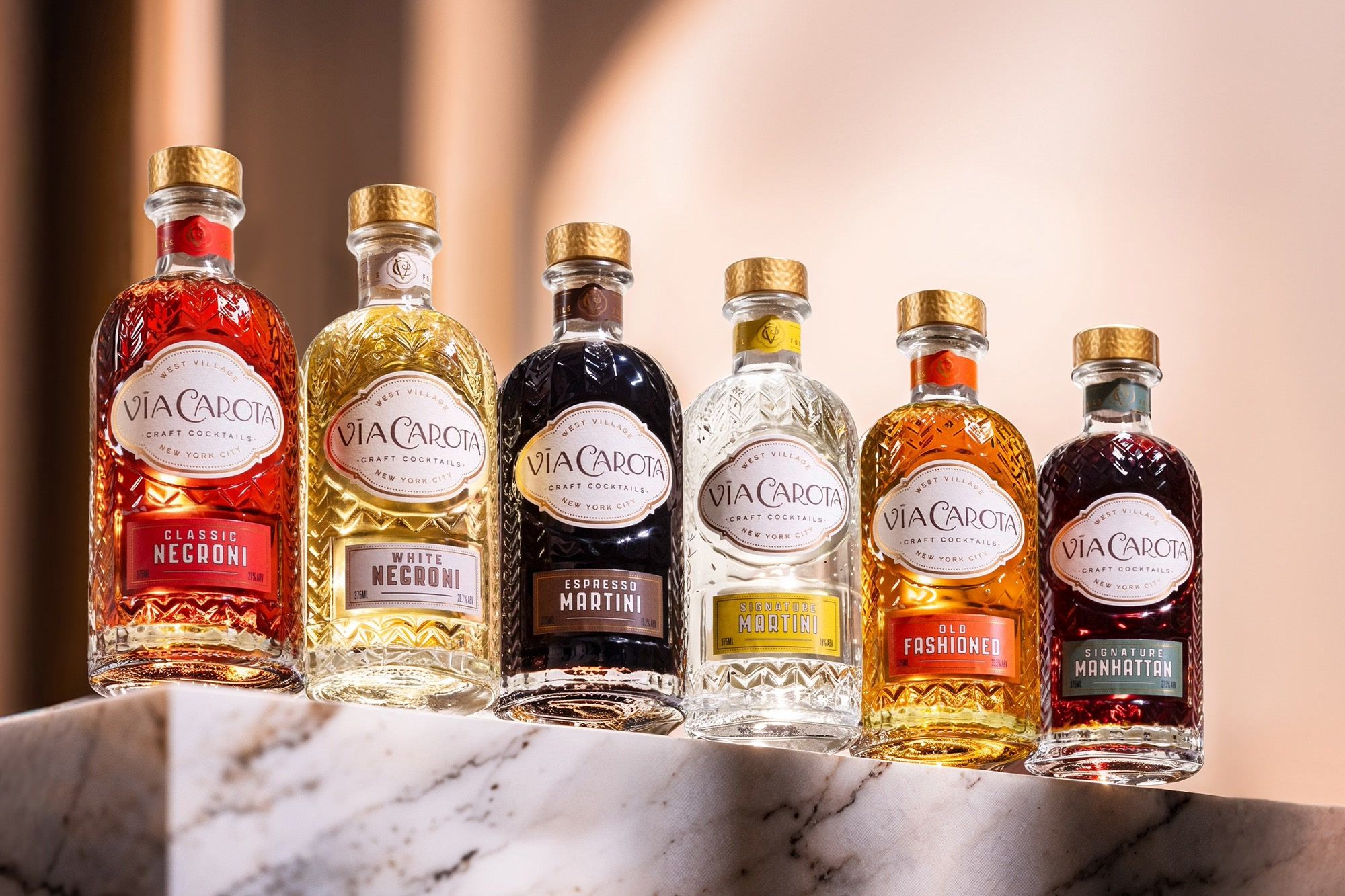 The Via Carota bottled cocktail collection lined on a marble ledge — case study by Chronos Studio.