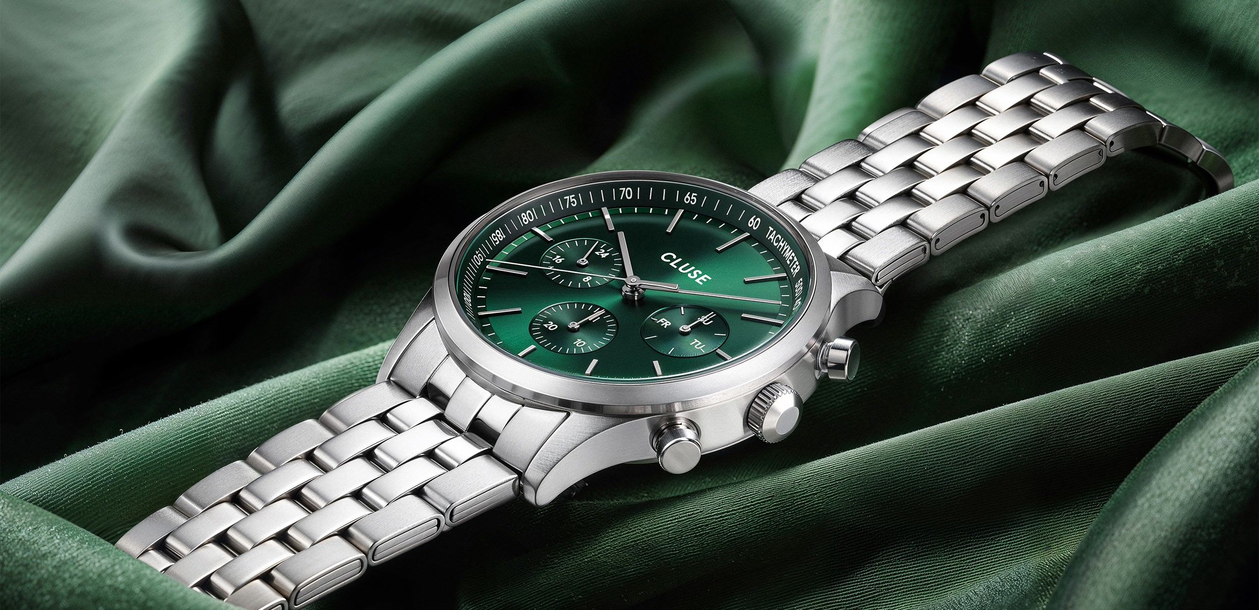 CLUSE emerald-dial chronograph resting on draped green satin — case study by Chronos Studio.