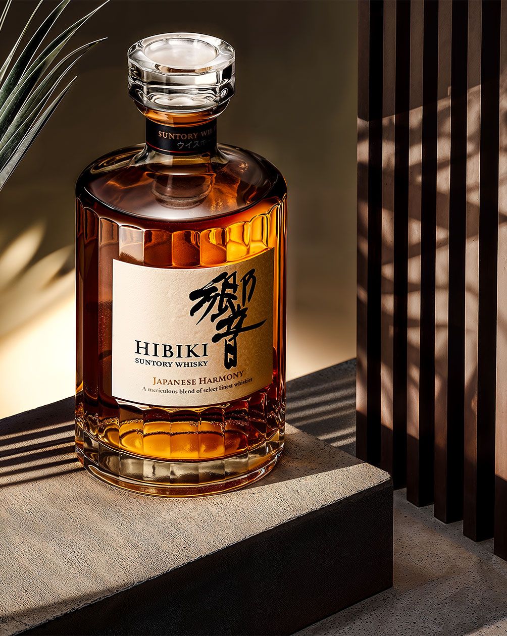 AI product photography of a whisky bottle lit against warm wood with amber reflections — Chronos Studio.