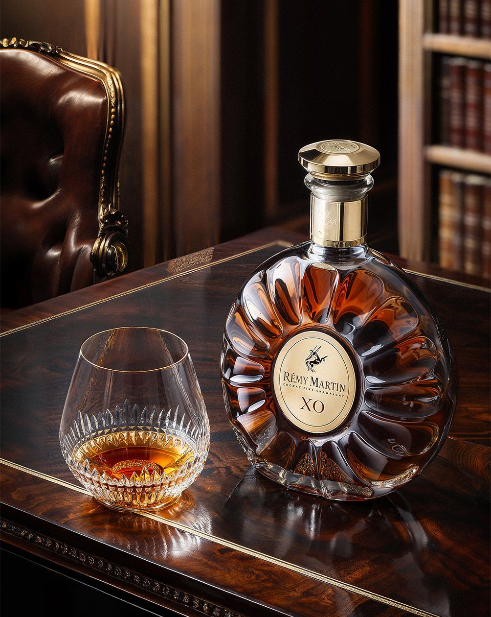 Portrait of the Rémy Martin XO decanter and crystal glass on the mahogany desk — Chronos Studio.
